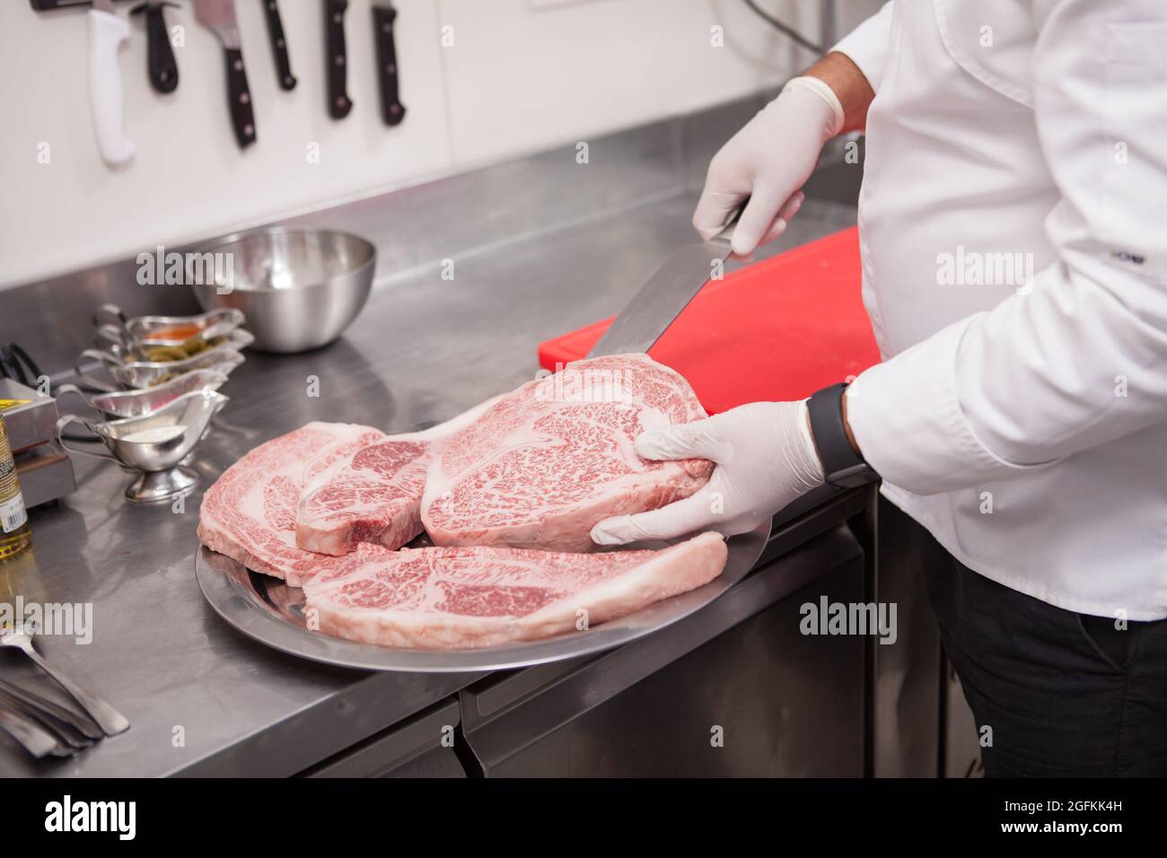 Cropped shot of a professional chef preparing marbled raw beef meat for ...