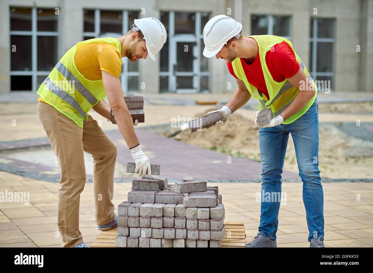 Skilled builders in cotton gloves choosing construction materials for pavement Stock Photo