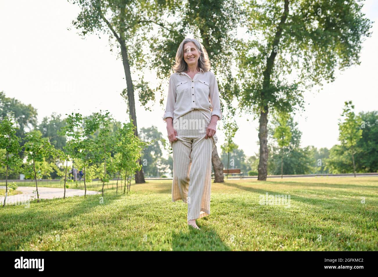 Woman walking barefoot on grass in park Stock Photo