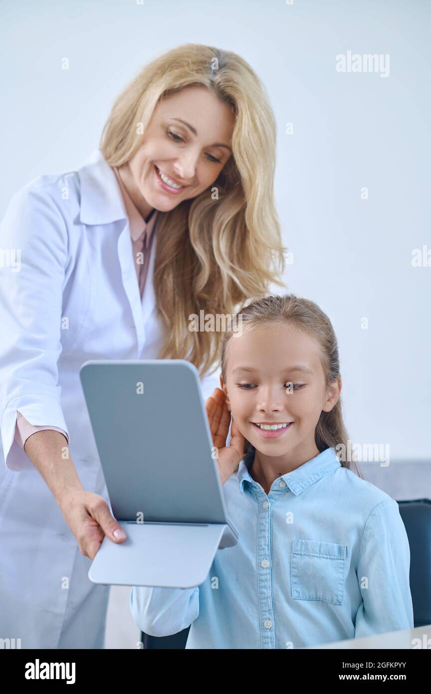 School age girl trying on hearing aid and doctor. Stock Photo