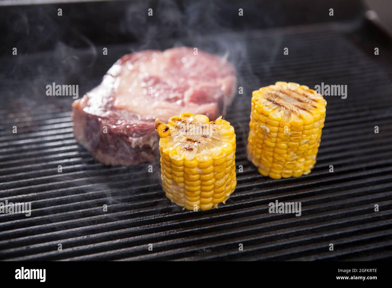 Fresh raw marbled beef grilling with sweet corn Stock Photo