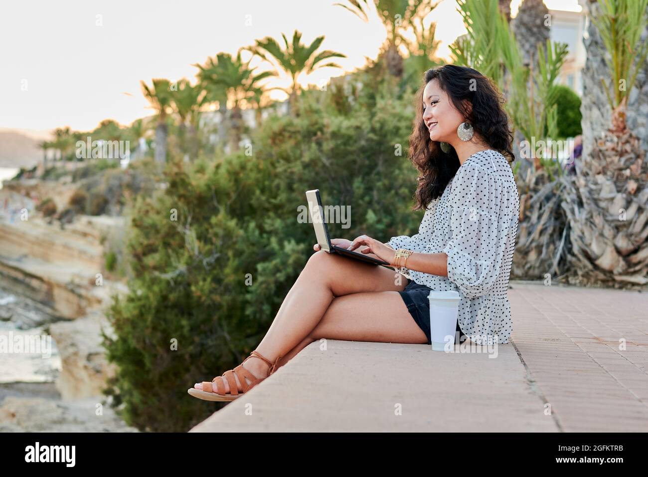 Young Asian woman works with her laptop remotely outdoors Stock Photo
