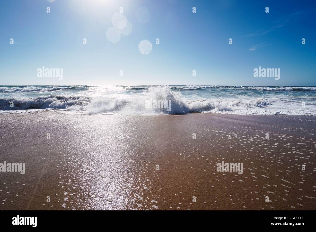 waves breaking on the shore of the beach with foam Stock Photo