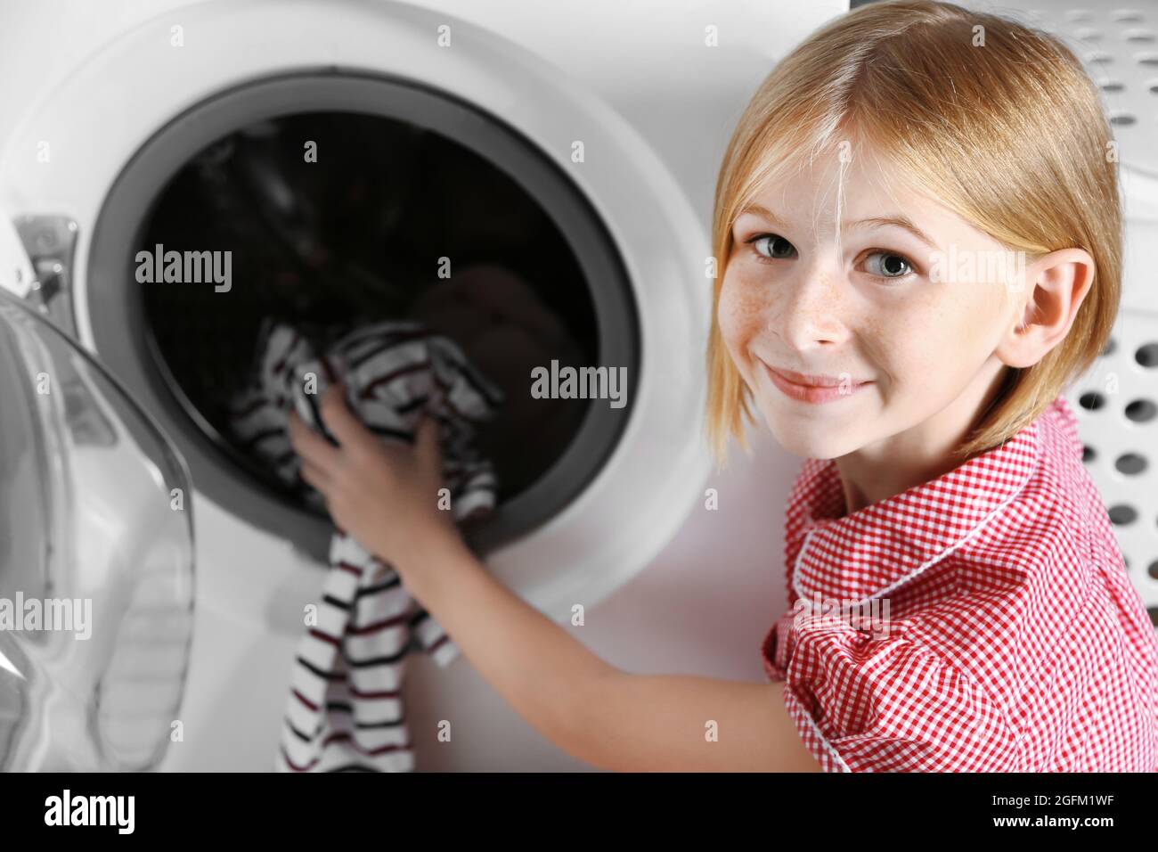 Small girl putting cloth into washing machine Stock Photo Alamy