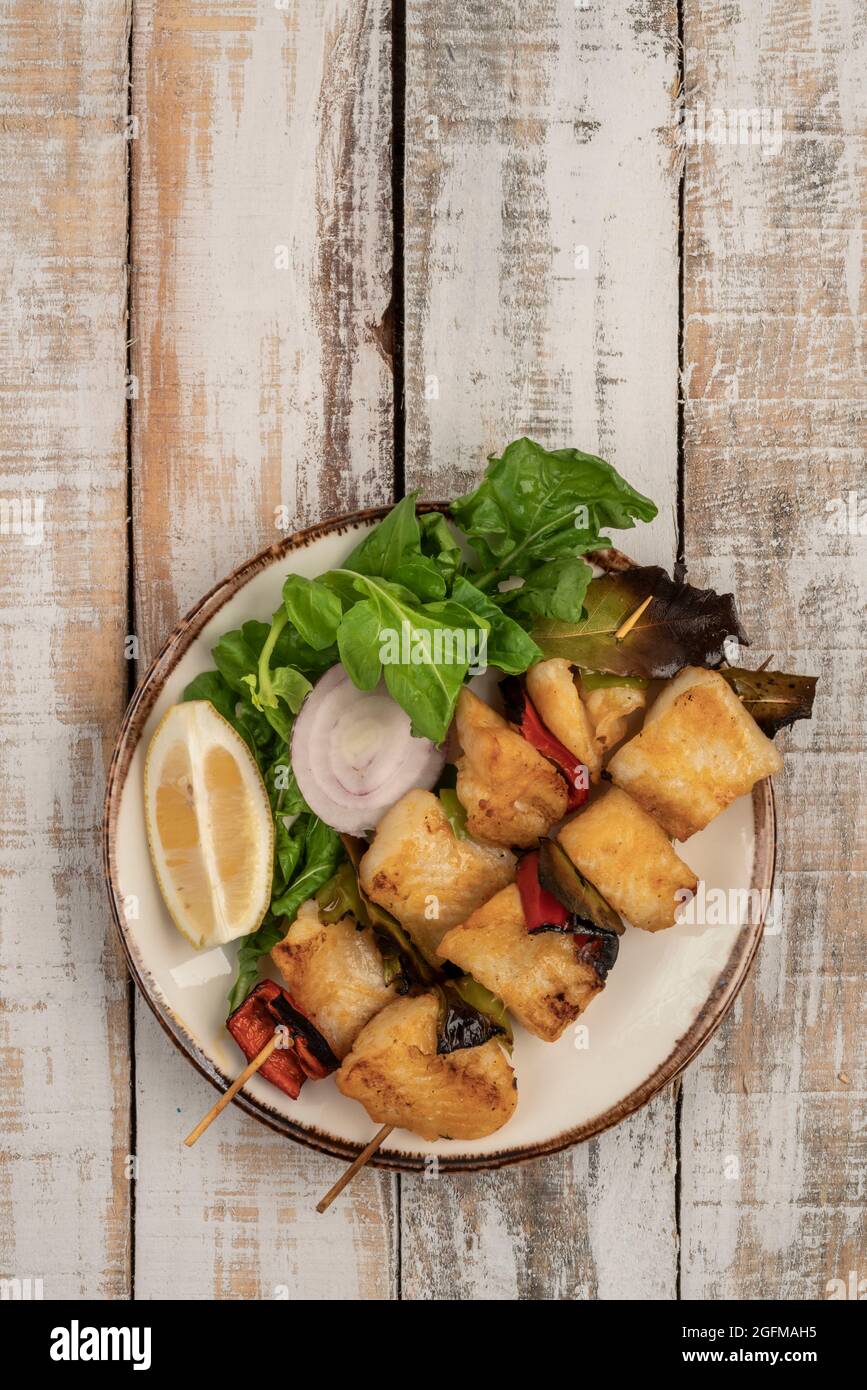 Skewed sole fish served with salad on a wooden table Stock Photo