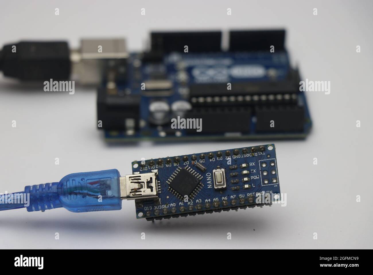 Arduino nano and arduino uno boards connected with programming cables ready to upload codes to make robot Stock Photo