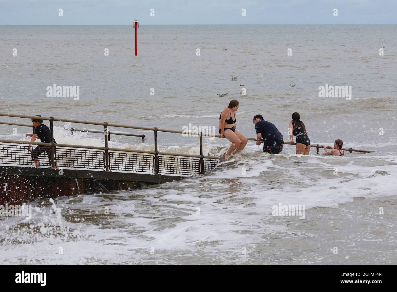Dymchurch, Kent, UK. 26 Aug, 2021. UK Weather: Overcast and windy in the seaside town of Dymchurch in Kent as brits on staycation enjoy splashing about in the sea. Photo Credit: Paul Lawrenson/ Alamy Live News Stock Photo