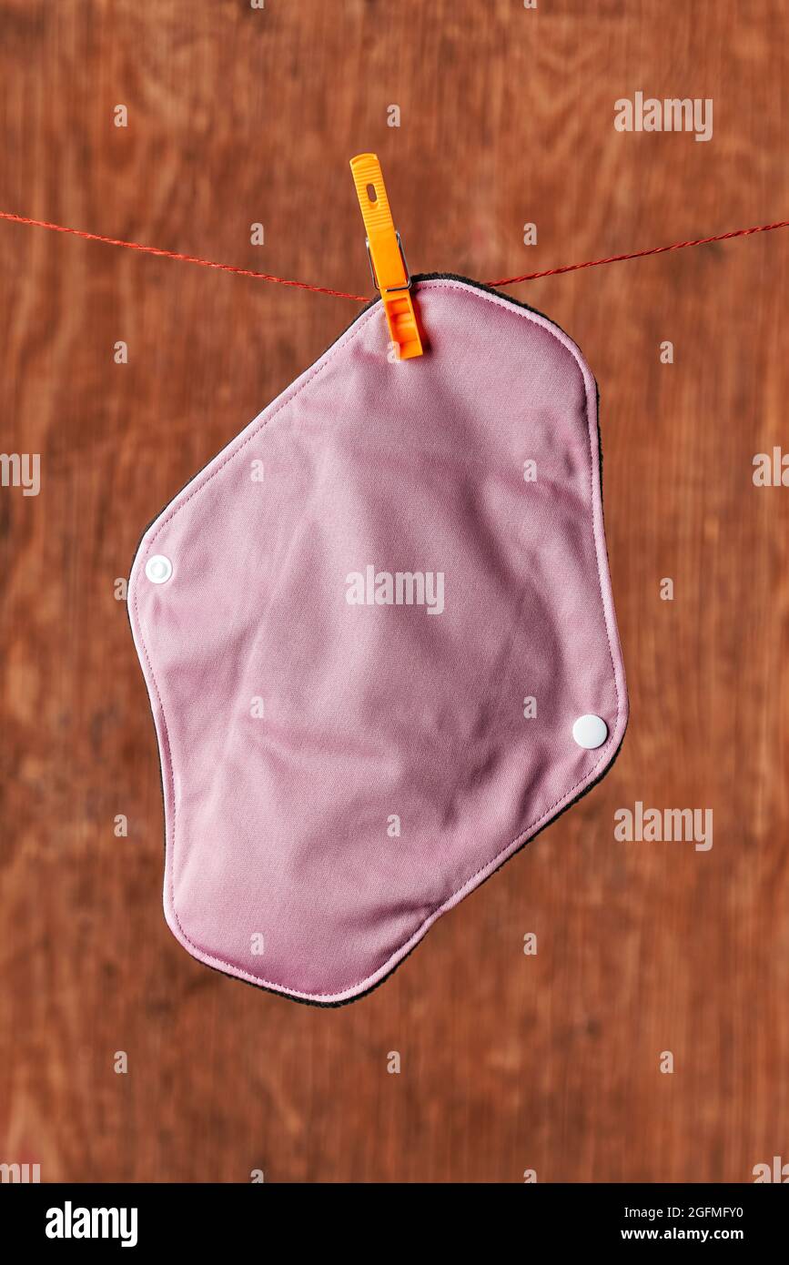 closeup of a pink cloth menstrual pad hanging on a clothes line using a clothespin Stock Photo