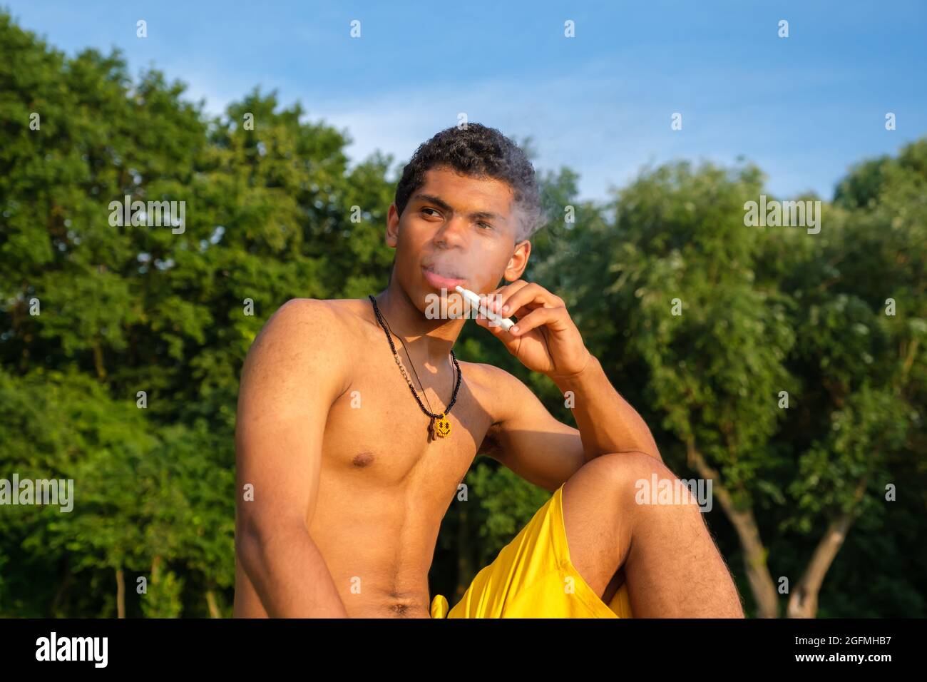 African-American young man vaping e-cigarette with e-liquid Stock Photo