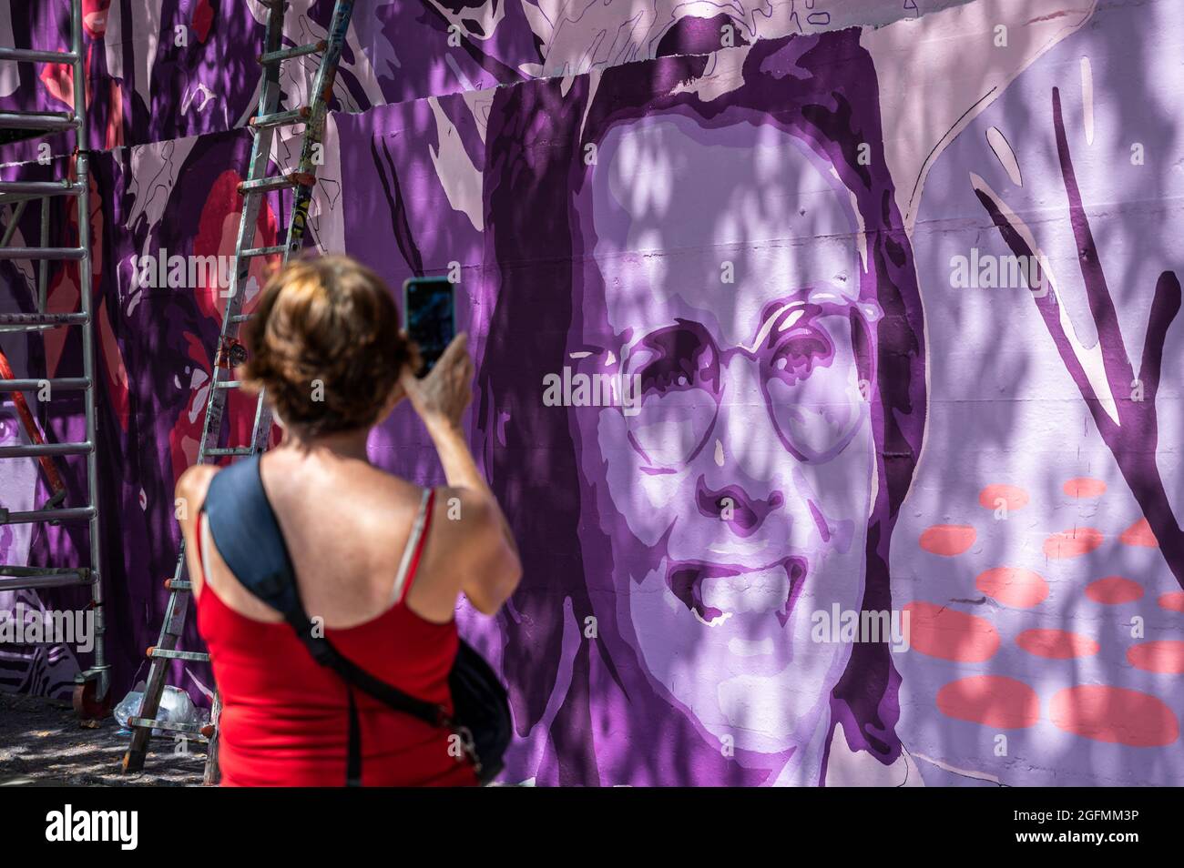 Madrid, Spain, 26/08/2021, A woman takes pictures to a feminist mural that is being repainted by members of UNLOGIC artistic group. The mural appeared vandalized during the past International Women's Day and represents famous women from around the world, with the faces of 15 women who are part of history for their fight in favor of equality: Angela Davis, Frida Kahlo, Nina Simone, Rigoberta Menchu, Lucia Sanchez Saornil, Rosa Arauzo, Valentina Tereshkova, Chimamanda Ngozi, Emma Goldman, Kanno Sugato, Liudmila Pavlichenko, Billy Jean King, Gata Cattana, Rosa Parks, and Comandanta Ramona. Stock Photo