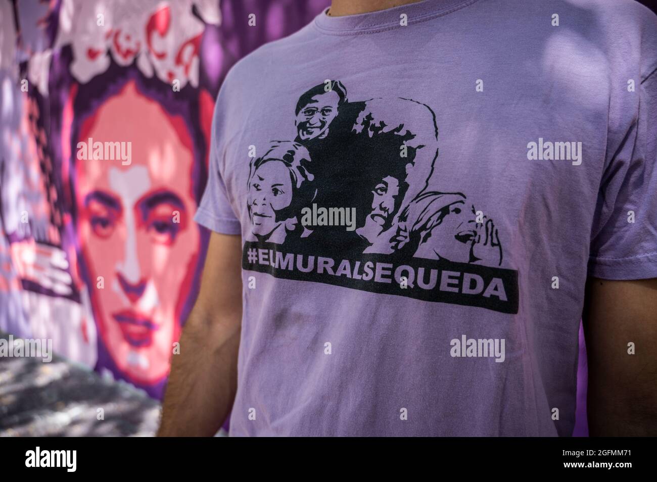 Madrid, Spain, 26/08/2021, A man wearing a shirt with the slogan 'the mural stays' stands next to a feminist mural that is being repainted by members of UNLOGIC artistic group. The mural appeared vandalized during the past International Women's Day and represents famous women from around the world, with the faces of 15 women who are part of history for their fight in favor of equality: Angela Davis, Frida Kahlo, Nina Simone, Rigoberta Menchu, Lucia Sanchez Saornil, Rosa Arauzo, Valentina Tereshkova, Chimamanda Ngozi, Emma Goldman, Kanno Sugato, Liudmila Pavlichenko, Billy Jean King, Gata Catta Stock Photo