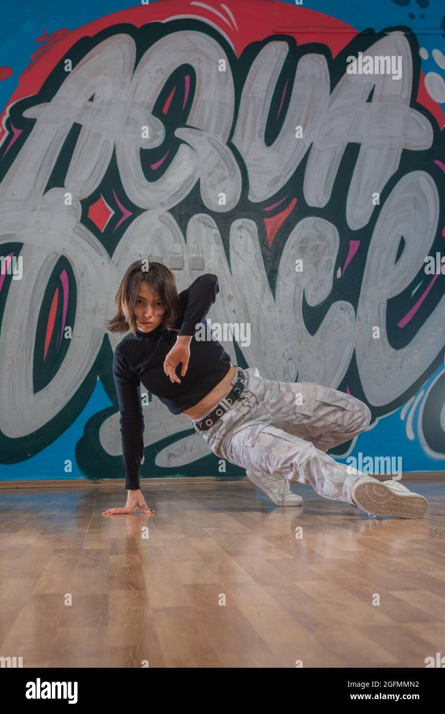 Dance is life. Happiness in moving. Sporty teenage girl, brick wall  background with free space. Hip hop lifestyle, flexible dancing young  female, breakdance concept Stock Photo