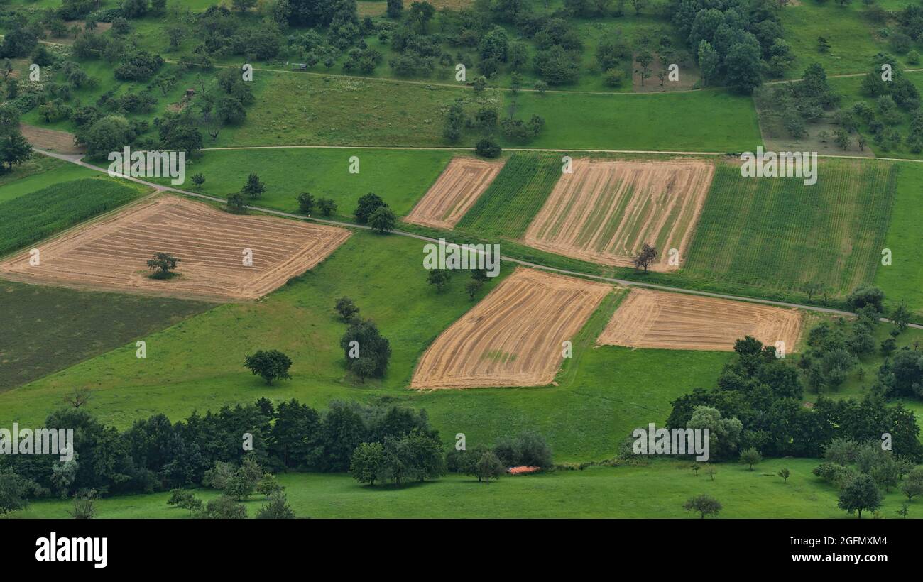 Aerial view of brown colored harvested agricultural fields surrounded by green meadows and fields on the foothills of northern Swabian Alb, Germany. Stock Photo