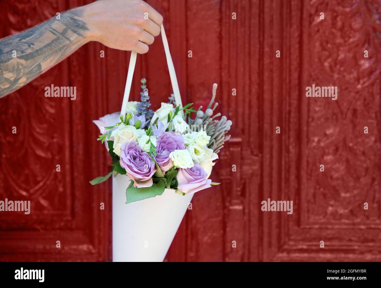 Male hand holding beautiful bouquet on door background Stock Photo - Alamy