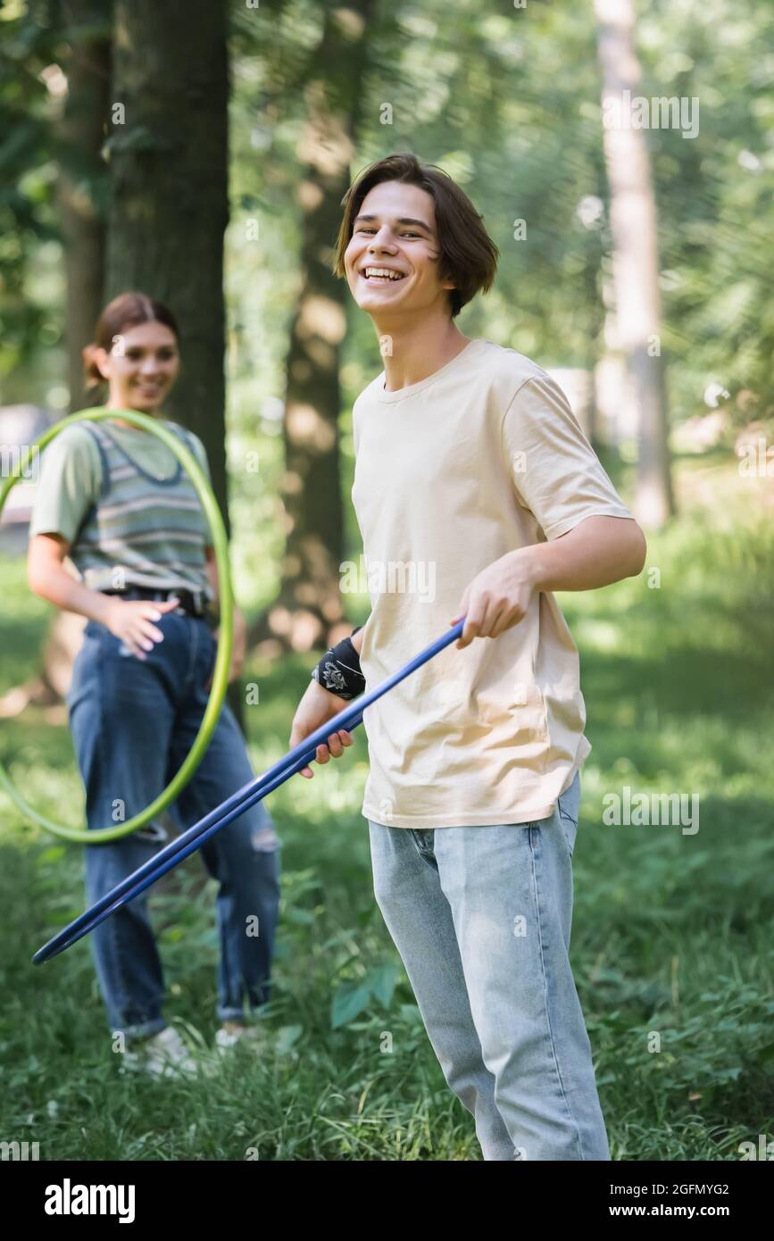 Positive teenager holding hula hoop near blurred friend Stock Photo