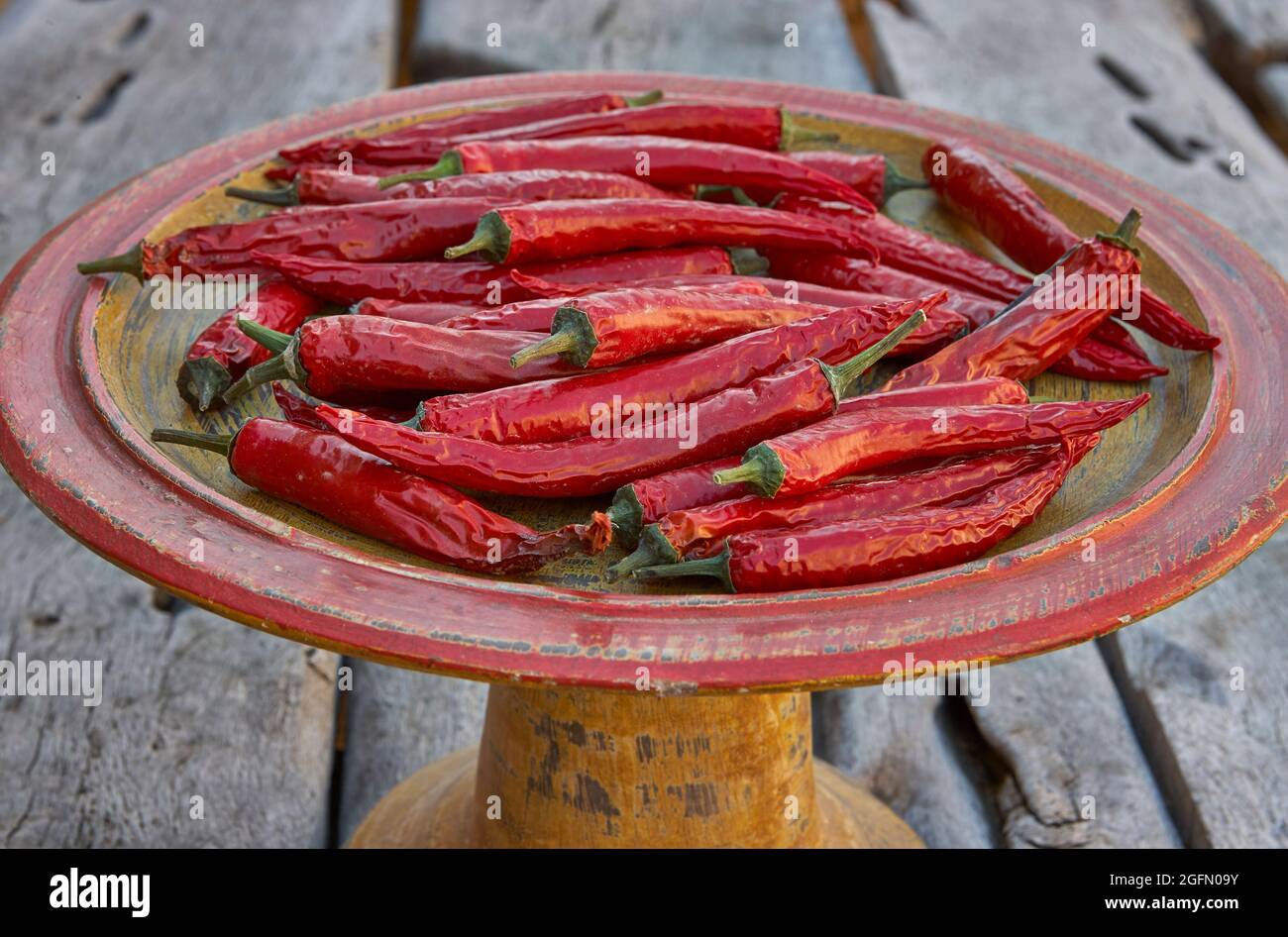 Italian long red peppers drying on earthenware plate Stock Photo