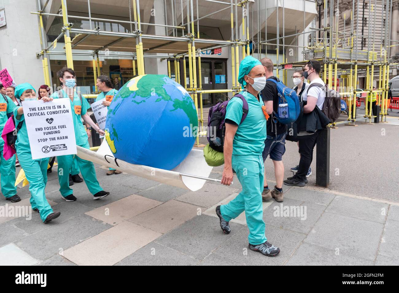 Doctors carry the world on a stretcher during Extinction Rebellion's Impossible Rebellion protest continues march to the Department for Business Energy and Industrial Strategy under the banner of Stop The Harm protesting against climate change, global warming, and plans to target the root cause of the climate and ecological crisis and to demand the government divest from fossil fuel companies. (Photo by Dave Rushen / SOPA Images/Sipa USA) Stock Photo