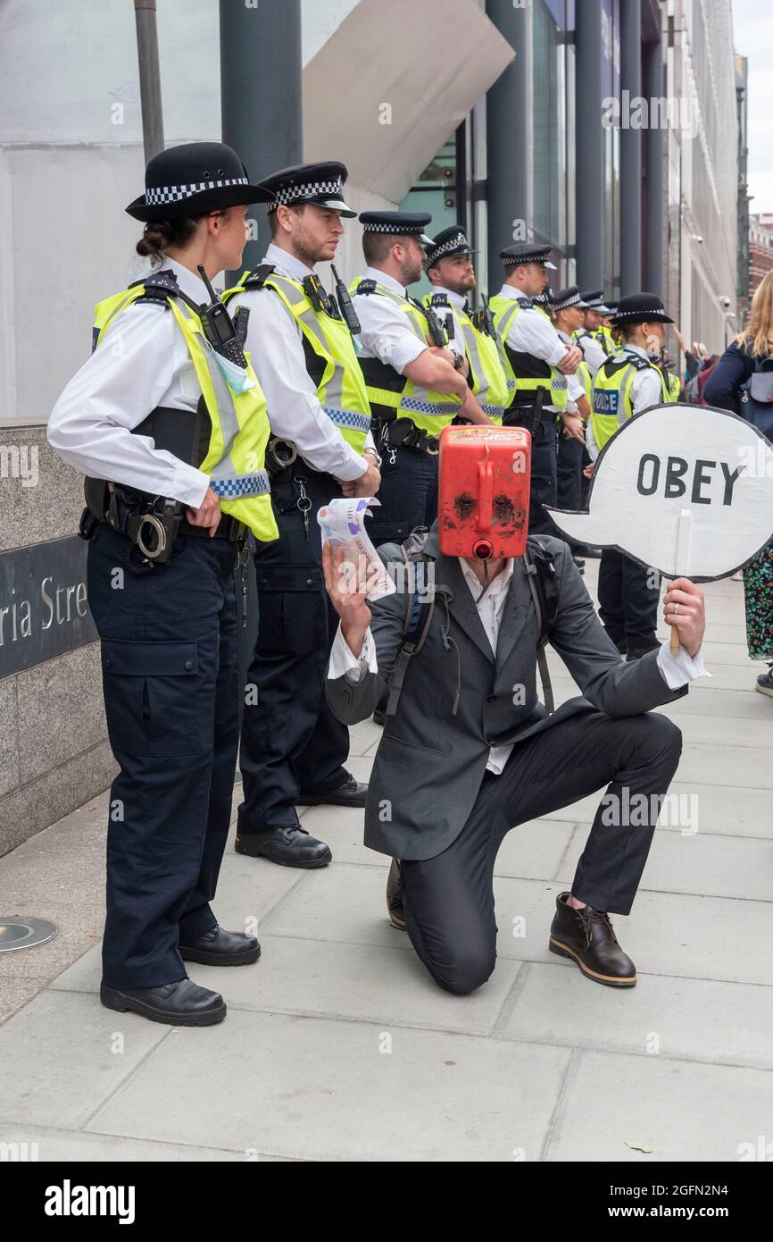 A protester with a fuel can as a mask protests at the foot of a police office with a sign saying ‘Obey’ during Extinction Rebellion's Impossible Rebellion protest continues march to the Department for Business Energy and Industrial Strategy under the banner of Stop The Harm protesting against climate change, global warming, and plans to target the root cause of the climate and ecological crisis and to demand the government divest from fossil fuel companies. (Photo by Dave Rushen / SOPA Images/Sipa USA) Stock Photo