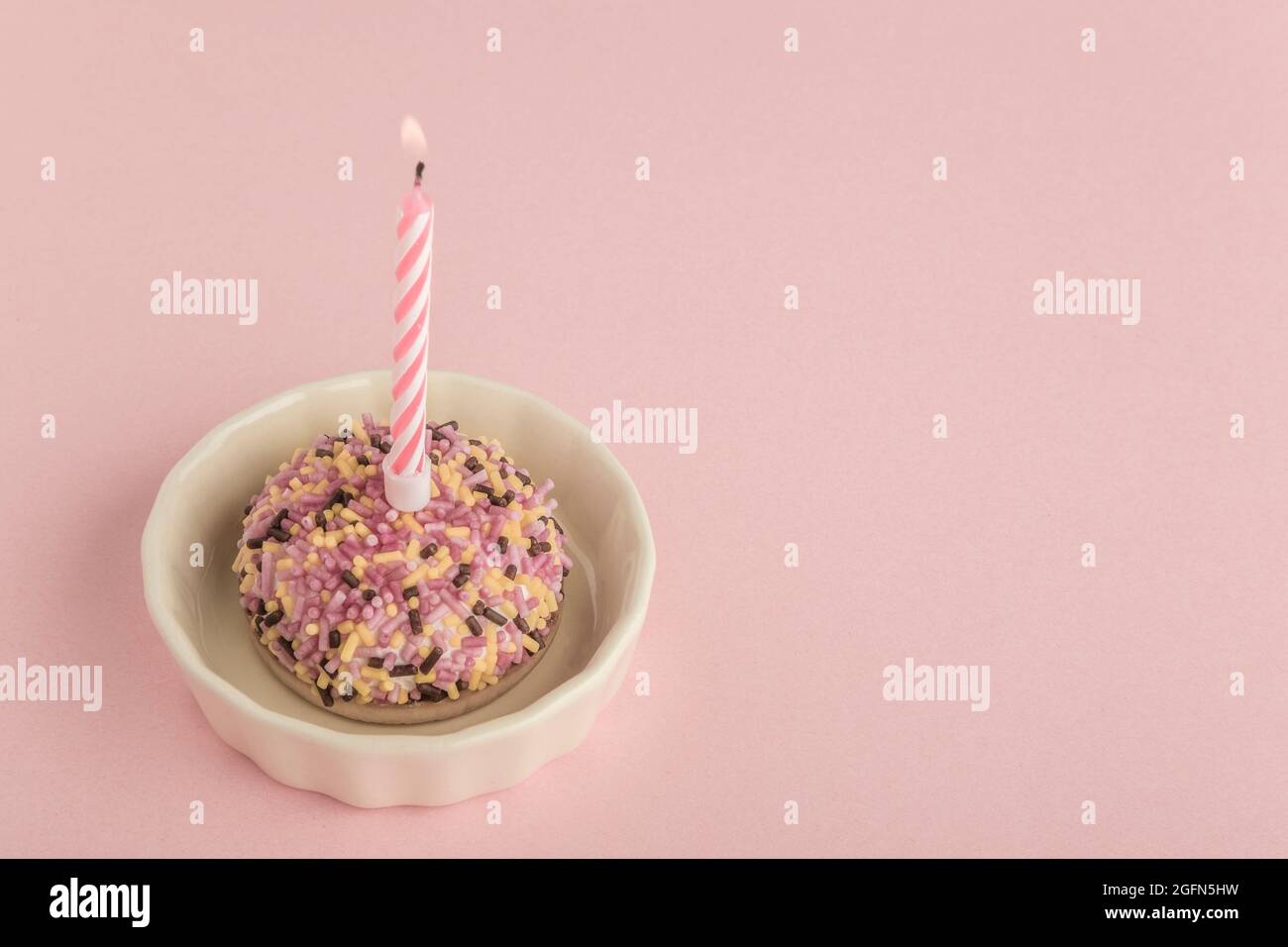 A small and colorful birthday cake with one candle on pink Stock Photo ...