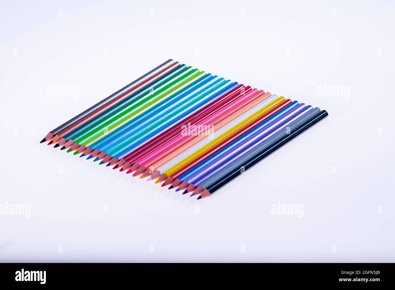 24 multicolored crayons on a white background, neatly arranged and sharpened. Hello School Stock Photo