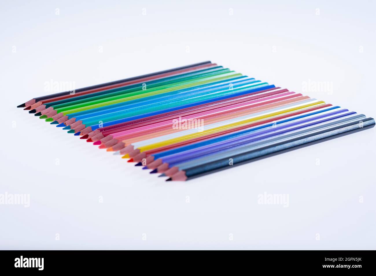 24 multicolored crayons on a white background, neatly arranged and sharpened. Hello School Stock Photo