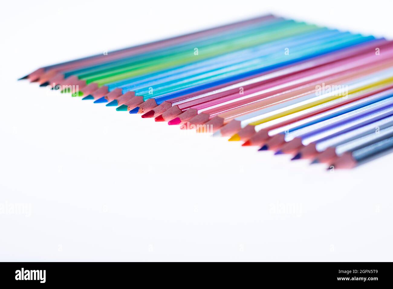 24 multicolored crayons on a white background, neatly arranged and sharpened. Hello School Stock Photo