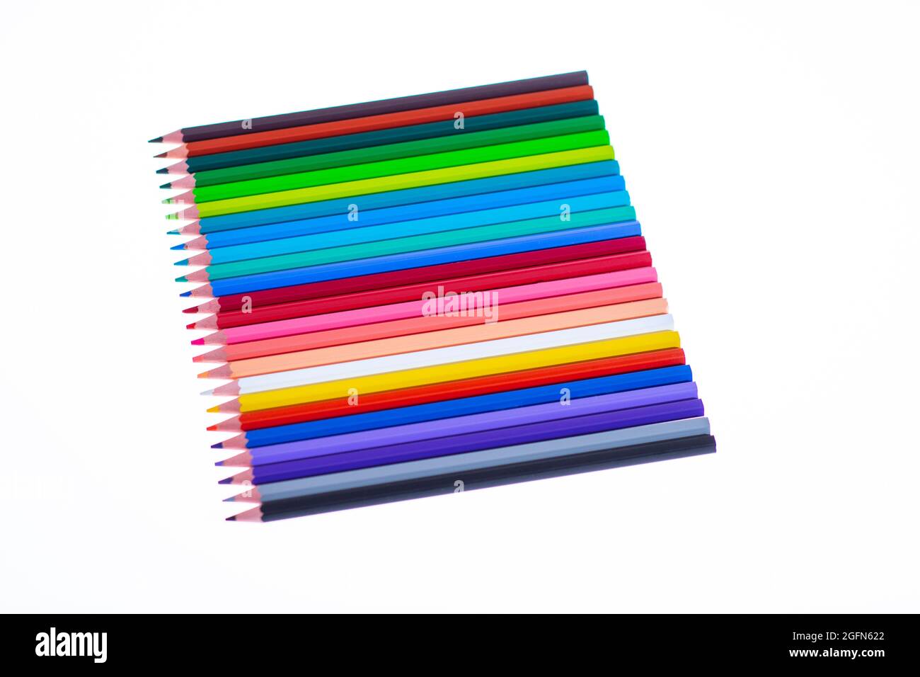 24 multicolored crayons on a white background, neatly arranged and sharpened. Hello School Stock Photo