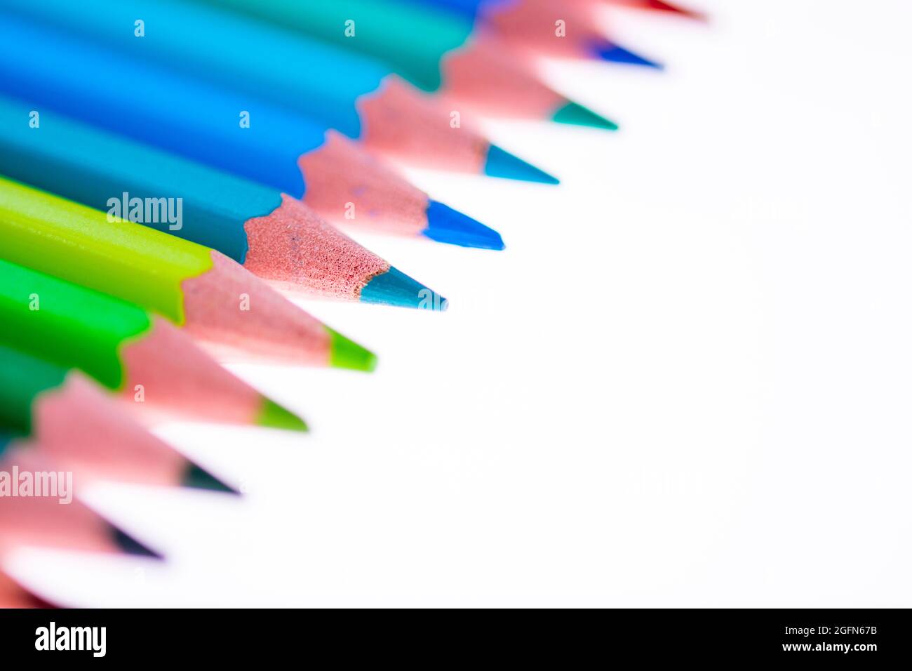 24 multicolored crayons on a white background, neatly arranged and sharpened. Hello School Stock Photo