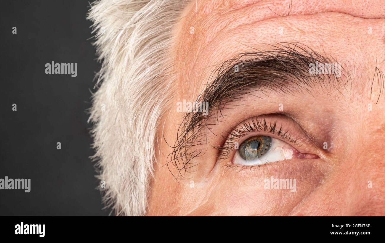 an elderly man's eye close up, wrinkles and crow's feet aging concept. Stock Photo