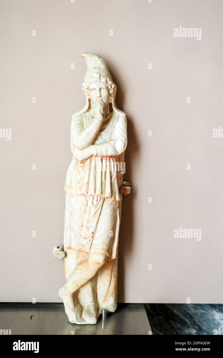Attis-shaped support - The sculpture, which still conserves some of its original red colouring, depicts Attis against a wide plaster, wearing a Phrygian cap, long trousers (anaxyrides) and a long-sleeved tunic fastened with a belt at the waist. The god's right leg is crossed over his left, his right hand closed in a fist under his chin, and his left hand supports his right elbow. According to several authors, these statues were not simple decorative elements to support table tops but instead veritable cultic objects or, according to others, depictions of eastern barbarian prisoners. This image Stock Photo