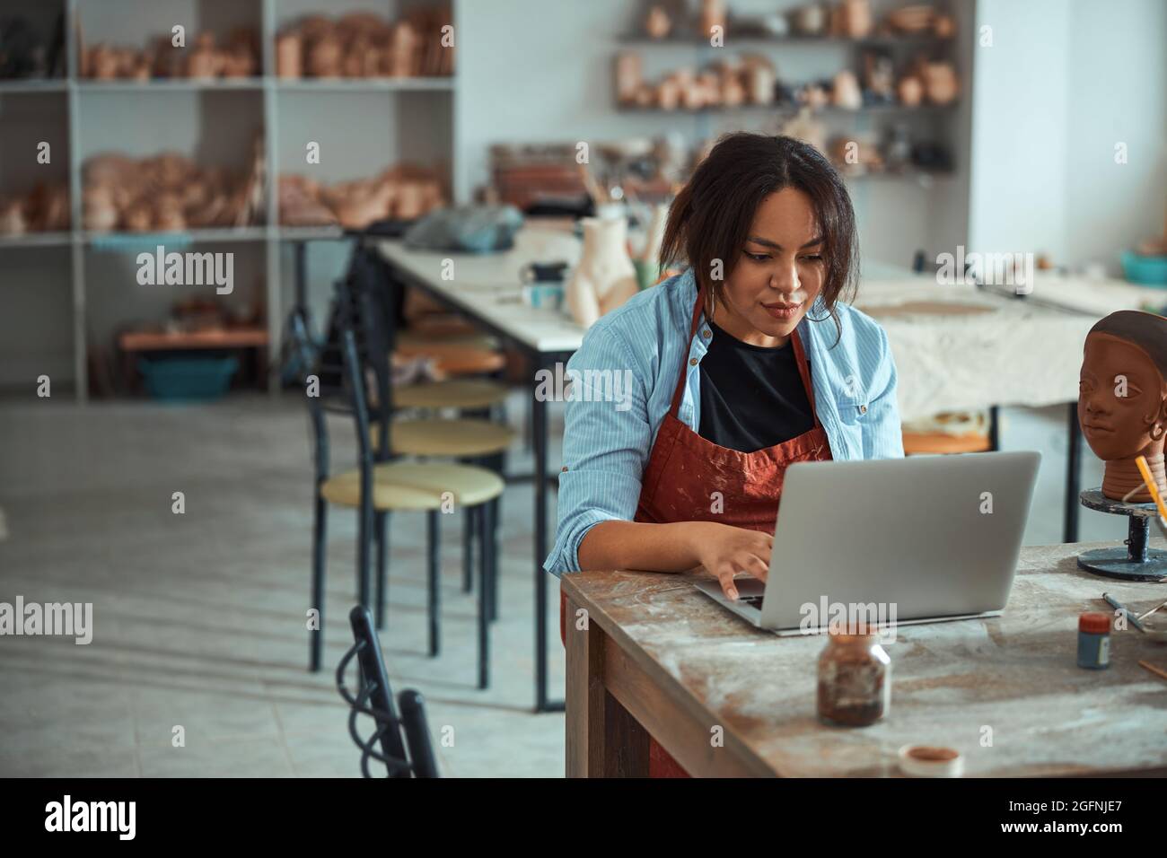 Charming female potter using notebook in pottery workshop Stock Photo