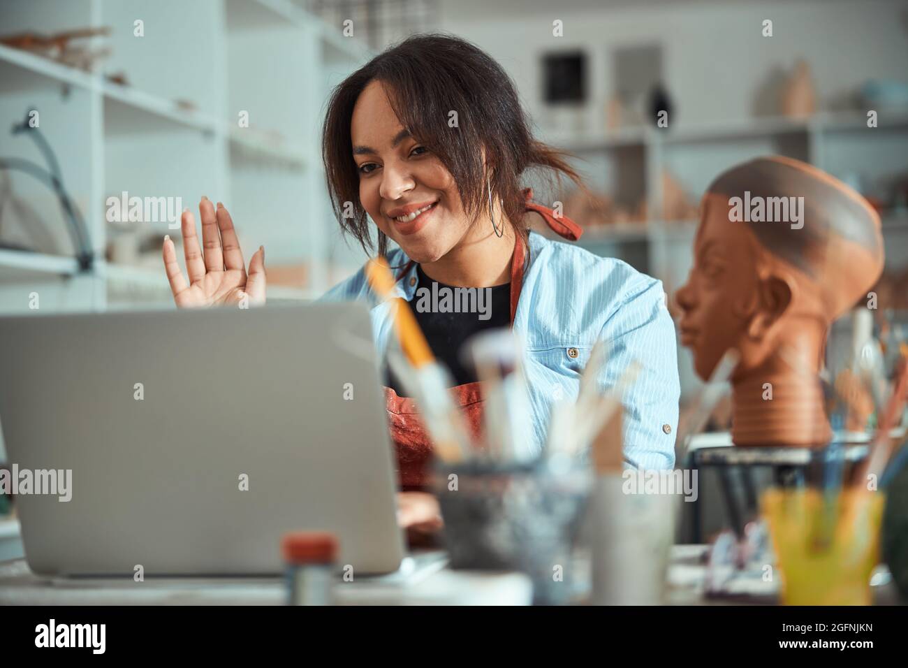 Nice female potter using laptop in pottery workshop Stock Photo