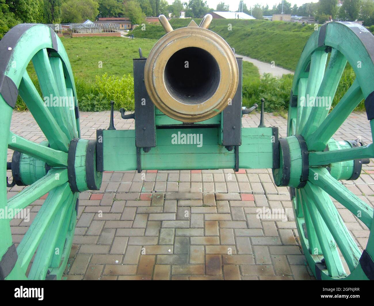 The vent of an old cannon on wooden wheels, opposite, standing on a stone pedestal Stock Photo
