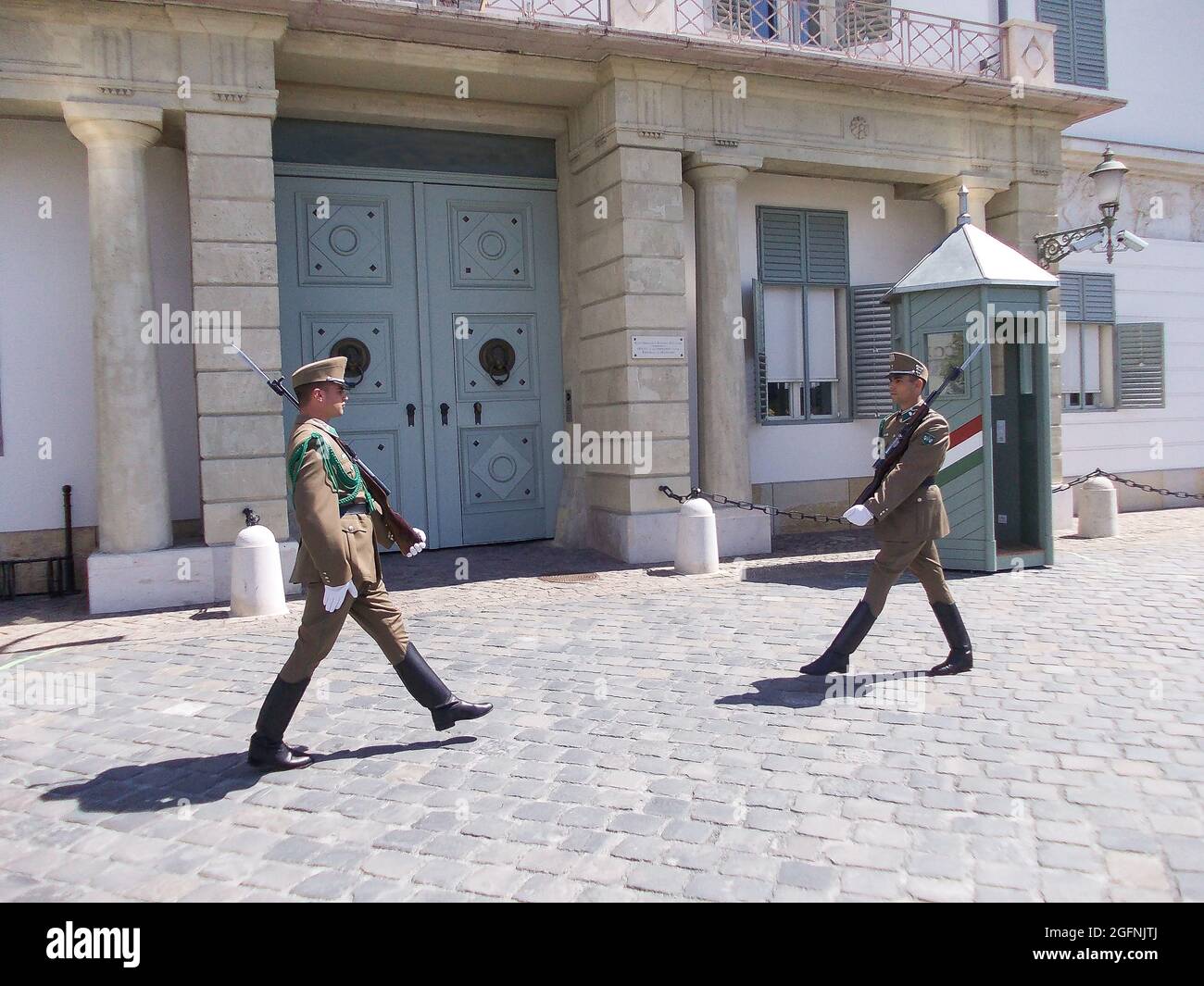 Two armed soldiers stand near the entrance to the building on guard and ...