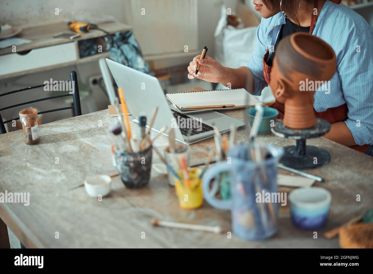 Female potter using notebook and taking notes in pottery workshop Stock Photo