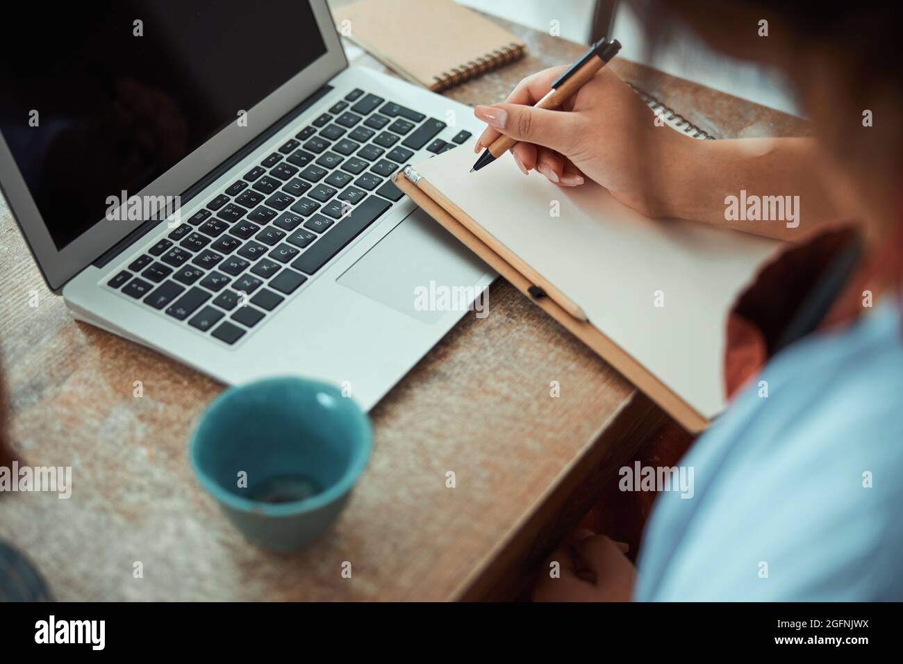 Female potter writing on notebook and using laptop in workshop Stock ...