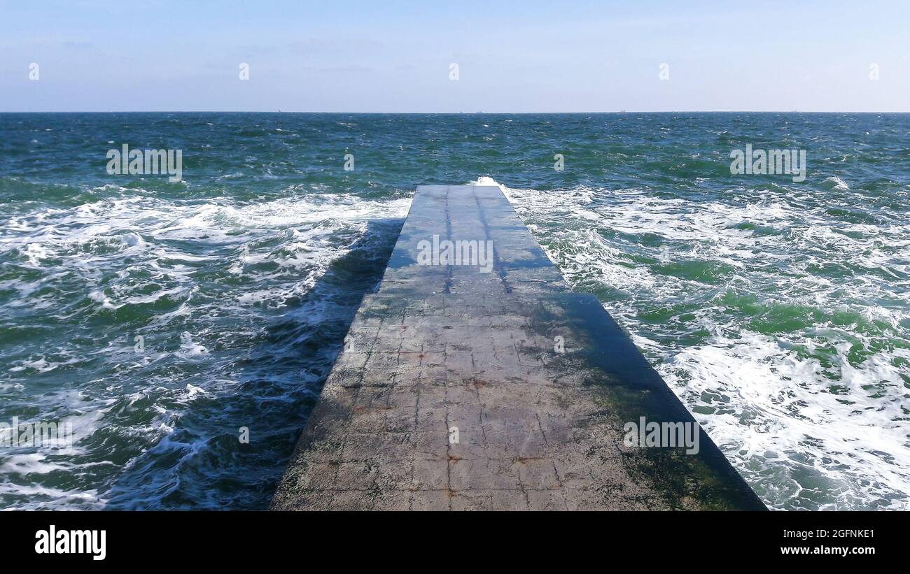 Stone uninhabited pier in cold winter blue sea against the blue sky and sea cold splay Stock Photo