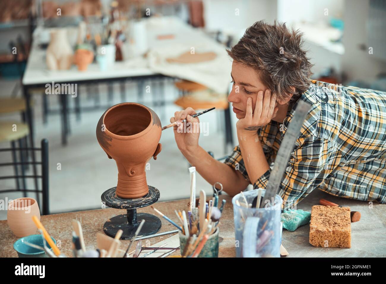 Nice female potter painting pottery in workshop Stock Photo - Alamy