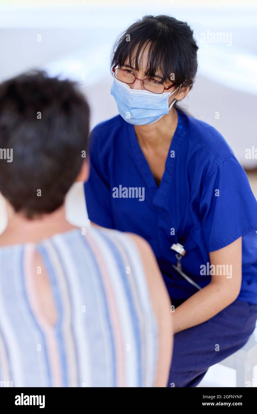Nurse wearing PPE mask talking to patient Stock Photo