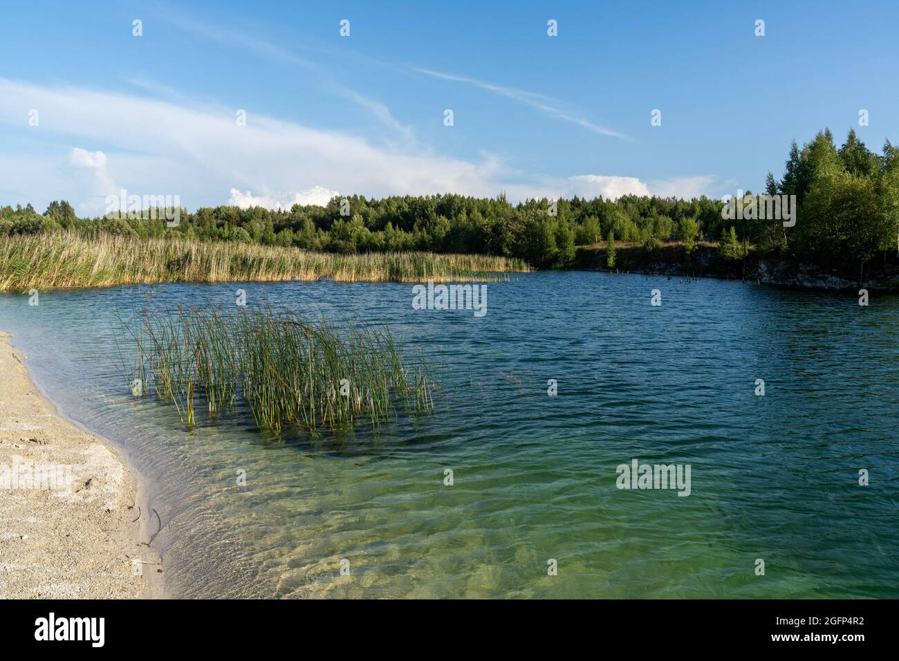A landscape of limestone and calm blue groundwater lake in an old quarry Stock Photo