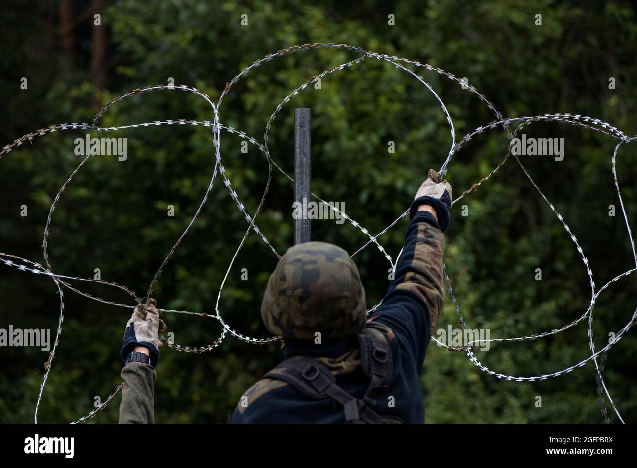 Zubrzyca Wielka, Poland. 26th Aug, 2021. Polish soldiers are seen building a fence along the border with Belarus.Polish army is building a 2.5 meters high barbed wire fence along its border and EU border at the same time with Belarus to stop the recent surge in illegal crossings, mainly by people from Iraq and Afghanistan. Warsaw and Brussels have accused Minsk of deliberately facilitating the passage of migrants into the European Union. (Photo by Attila Husejnow/SOPA Images/Sipa USA) Credit: Sipa USA/Alamy Live News Stock Photo