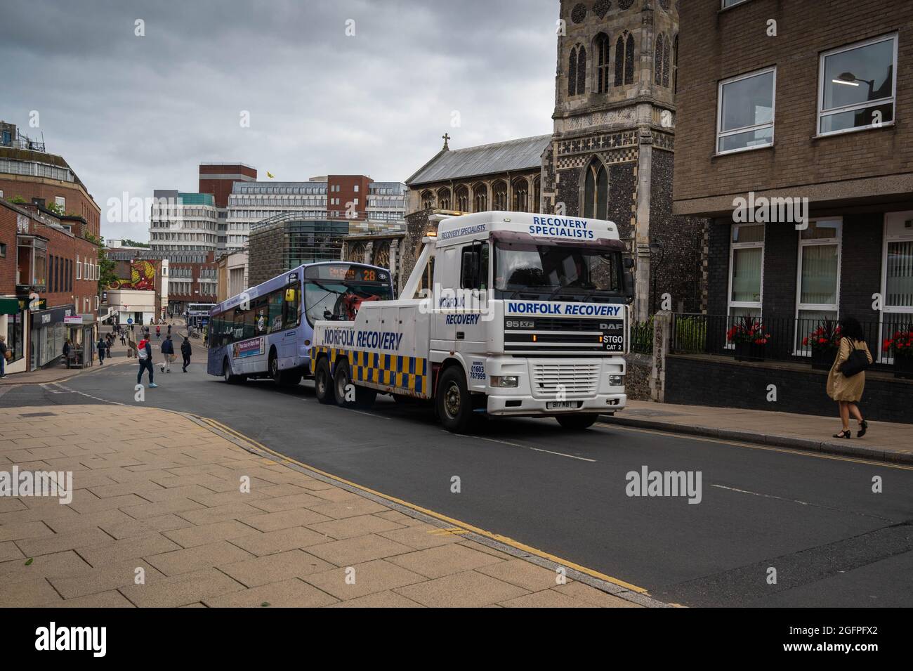 Heavy recovery truck towing a broken down single decker coach in Norwich city Stock Photo