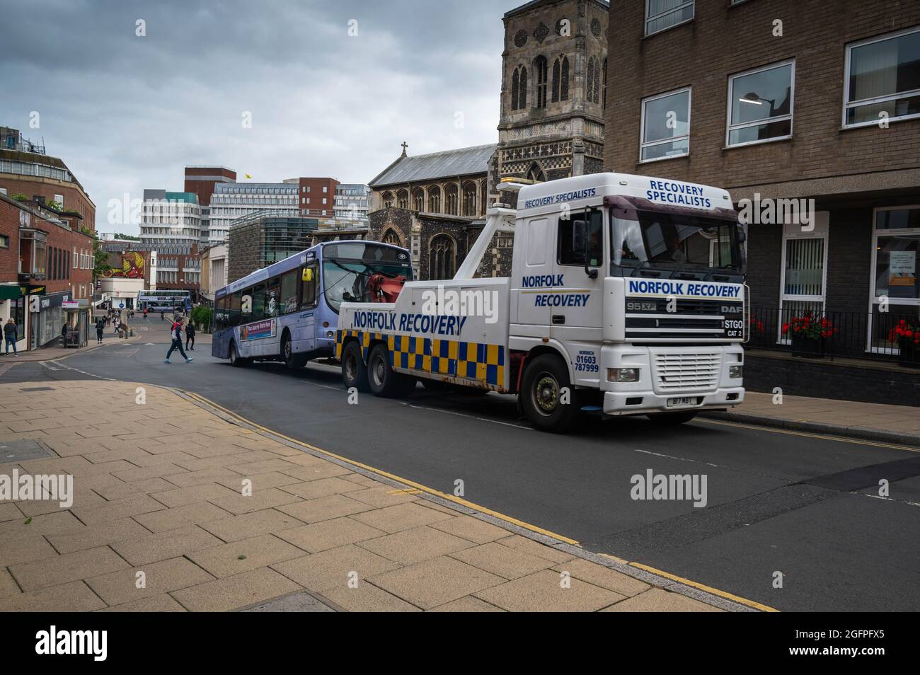 Heavy recovery truck towing a broken down single decker coach in Norwich city Stock Photo