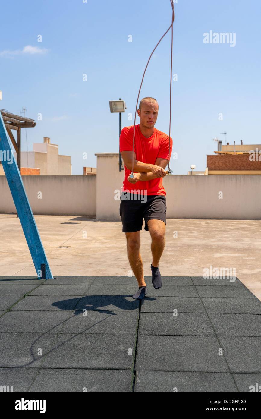 Rope jumping. Young sportsman having training and doing exercise ...
