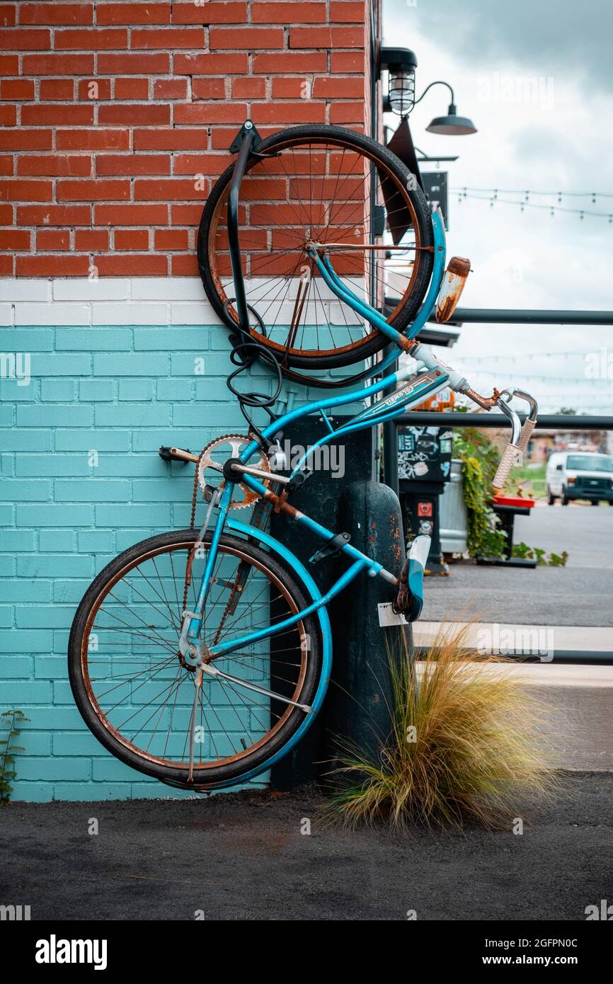 Vintage bicycle haning from one wheel on colorful brick wall at Camp North End in Charlotte, North Carolina, USA Stock Photo