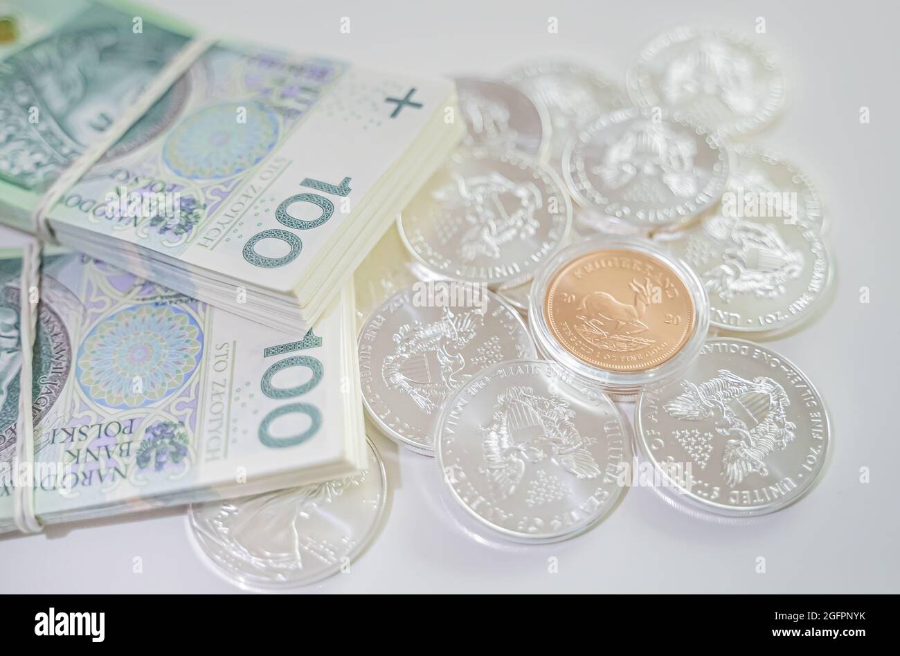 Warsaw, Poland 03.05.2021 piles of silver ducats with one gold on them next to two piles of paper money next to each other clamped with an elastic band. High-quality photo Stock Photo