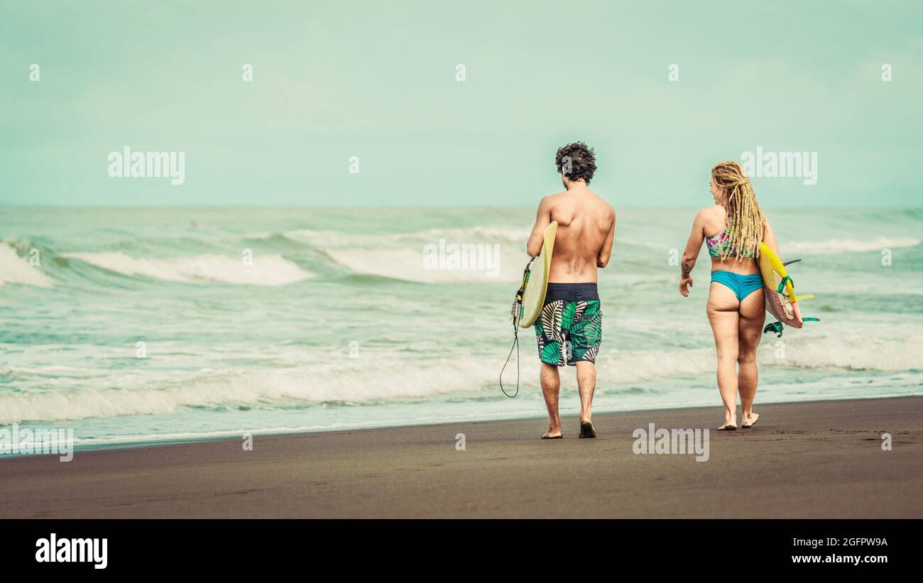 Playa Hermosa, Guanacaste, Costa Rica - 07.26.2020: A young man wearing shorts and a woman with blue bikinis are walking towards the sea Stock Photo