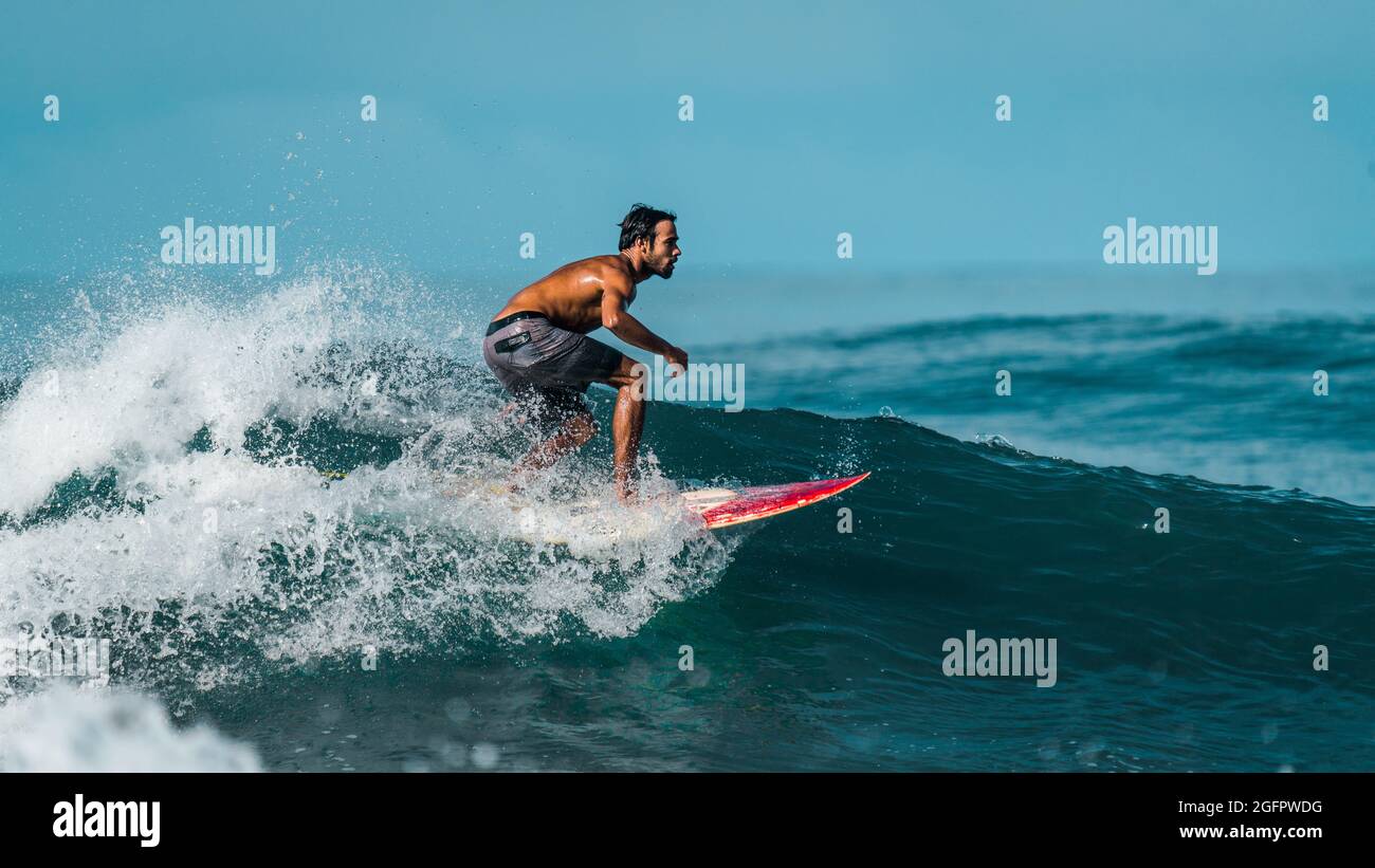 Playa Hermosa, Guanacaste, Costa Rica - 07.26.2020: A nice profile photo of a highly skilled surfer wearing shorts riding down a big wave Stock Photo