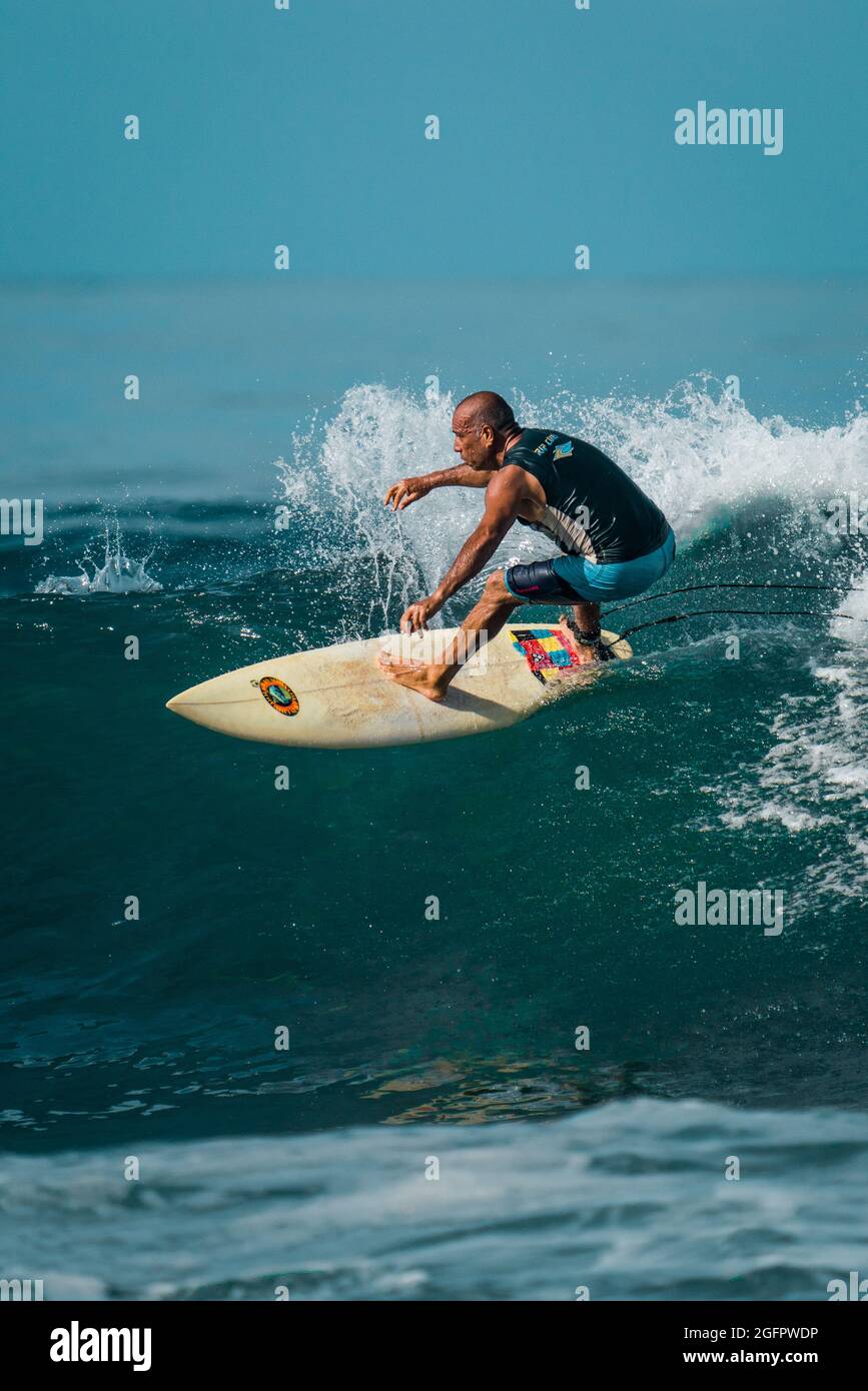 Playa Hermosa, Guanacaste, Costa Rica - 07.26.2020: A very fit and skilled senior surfer showing exceptional skills at making a turn at Pacific Coast Stock Photo