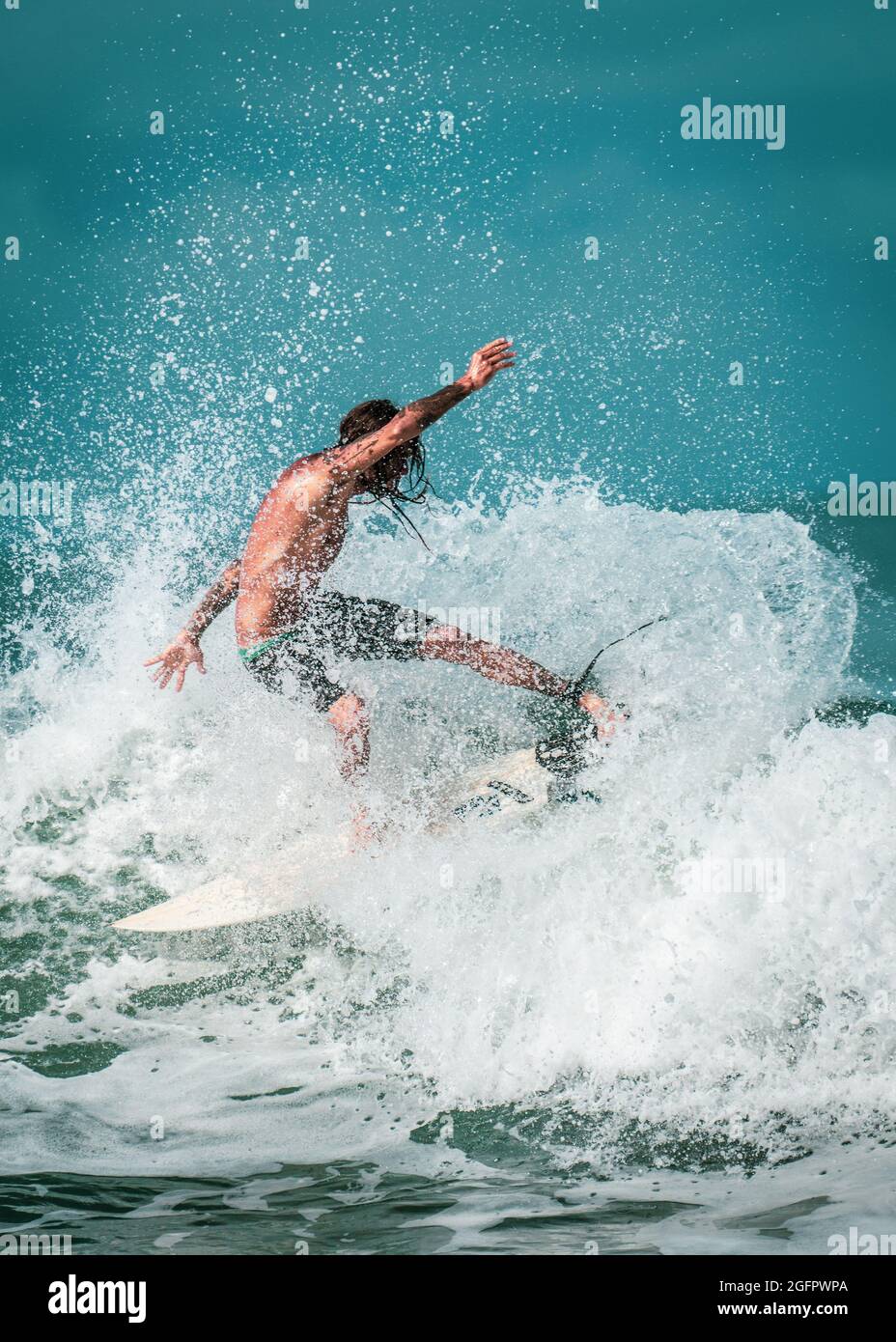 Playa Hermosa, Guanacaste, Costa Rica - 07.26.2020: A professional local surfer doing stunts and tricks on powerful splashy waves at the Pacific Coast Stock Photo